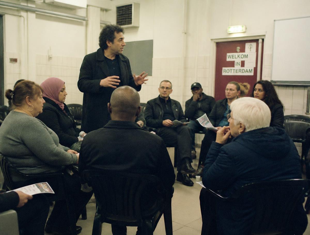 Neighbours seated in a community hall in Rotterdam discussing a local issue