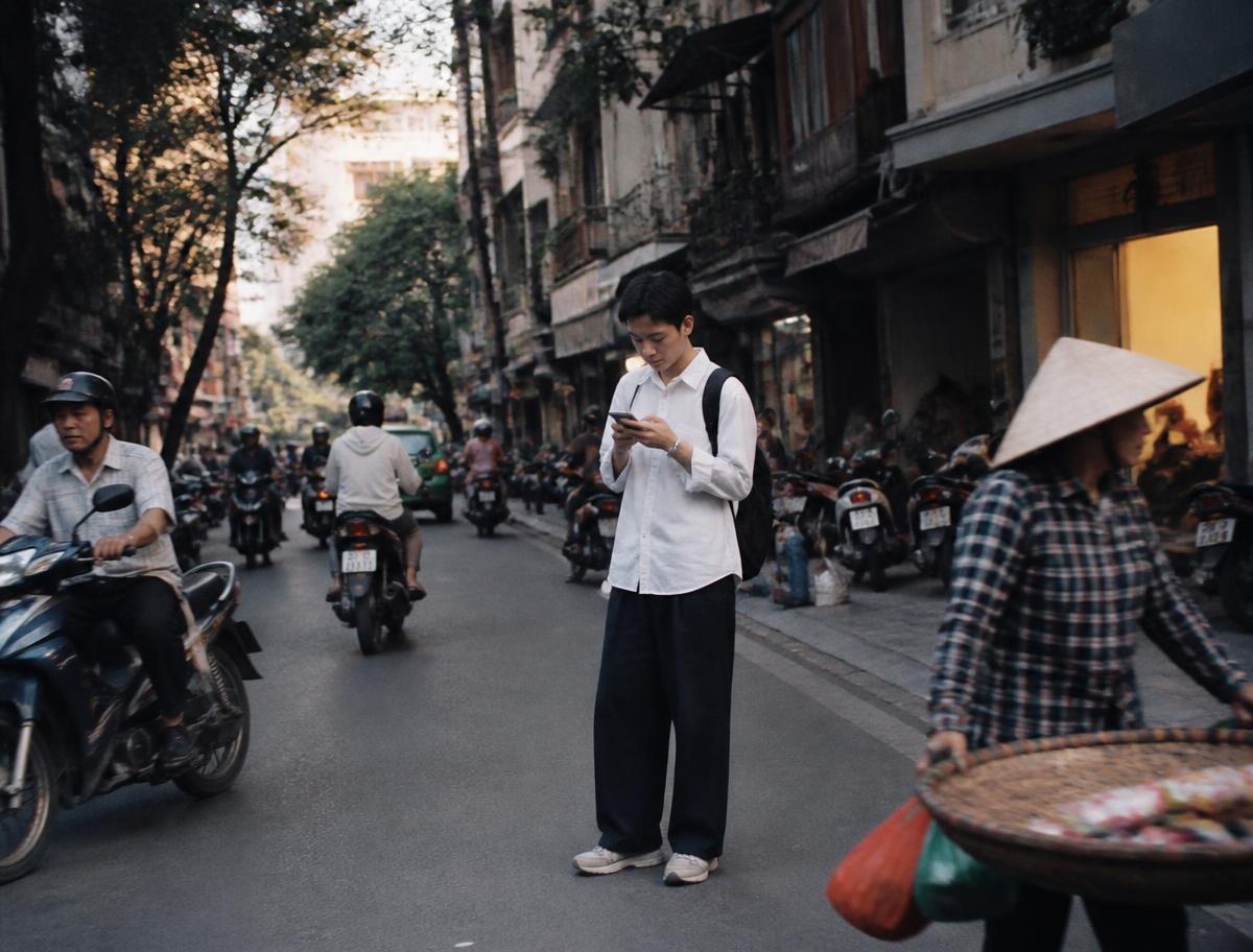 A man checking his phone on a busy street in Hanoi, Vietnam